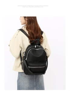 Close-up of black pebble grain PU leather backpack with silver zippers and multi-pocket design