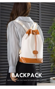 Detail of cream canvas backpack with brown leather base and drawstring closure