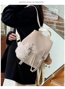 Detail view of beige backpack with silver studs, drawstring closure and plush pendant