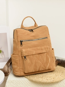 Détail d'un sac à dos en nylon plissé kaki avec plusieurs poches zippées et poignée