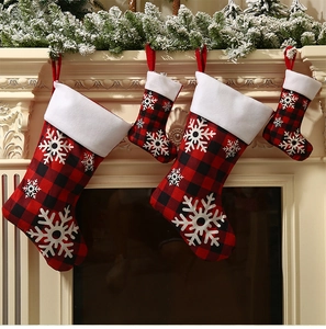Detailed view of four red black buffalo plaid Christmas stockings hanging on a fireplace