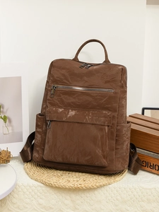 Vue macro du sac à dos vintage marron montrant la texture plissée et la poche latérale