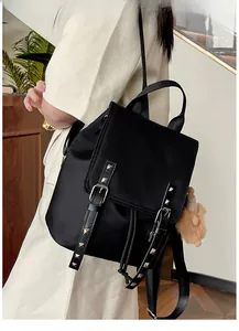 Detail of black nylon backpack with decorative silver studs and a plush ball pendant
