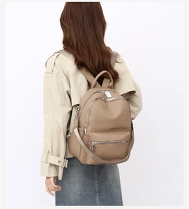 Detail view of khaki PU leather backpack with silver metal zippers and adjustable straps