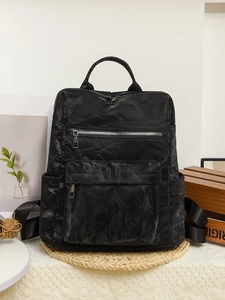 Détail du sac à dos vintage en cuir PU noir avec texture froissée sur un tapis
