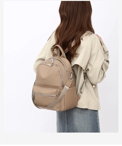Rear view of a model wearing the brown PU leather backpack with silver zippers and webbing straps