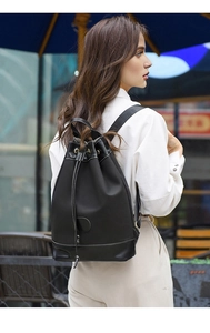 Detail of black oxford fabric backpack with contrast stitching and leather base