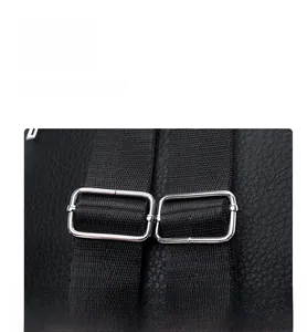 Close-up of silver metal adjustment buckles on a black lychee texture leather backpack