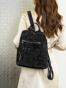 Vue détaillée du sac à dos vintage noir plissé avec fermetures éclair argentées sur modèle
