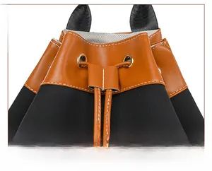 Close-up of brown litchi leather and black suede bucket bag with white stitching details