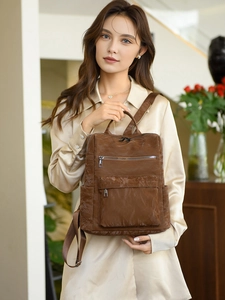 Détail d'un sac à dos vintage en cuir PU marron avec texture plissée et poches zippées