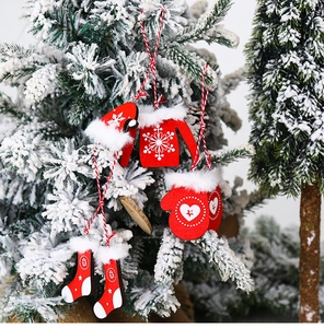 Detailed view of red wooden Christmas ornaments with white fur hanging on a snowy tree