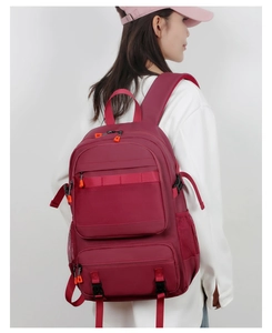 Detail view of burgundy ergonomic backpack featuring padded mesh straps and orange zipper pulls