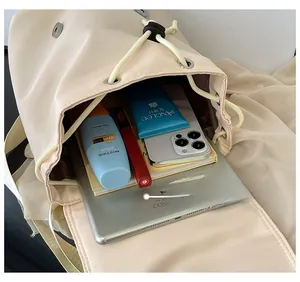 Detail shot of a large beige backpack showing high capacity for tablets and cosmetics
