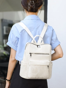 Détail d'un sac à dos blanc cassé minimaliste avec texture lisse et fermetures éclair noires