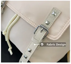 Detail of fabric design on beige backpack featuring silver rivets and metal buckle