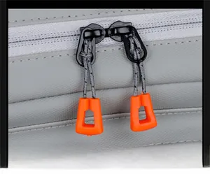 Macro shot of smooth dual metal zippers with bright orange pull cords on a grey backpack