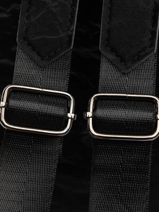 Détail des bretelles réglables en nylon avec boucles en métal argenté sur un sac à dos noir