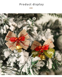 Close-up of handmade linen Christmas bows with gold bells on a snowy tree branch