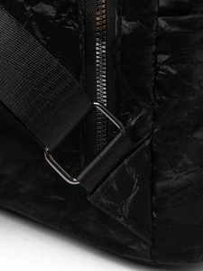 Détail du sac à dos en similicuir noir montrant les coutures renforcées et le zip métallique