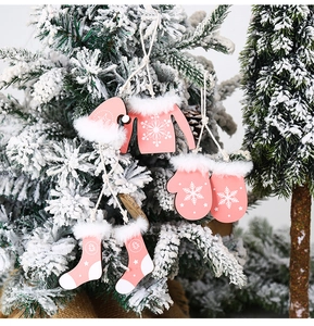 Pink wooden Christmas ornaments set with snowflake patterns hanging on a snowy tree branch