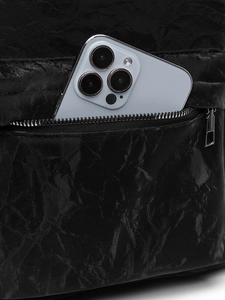 Vue détaillée de la texture plissée en similicuir noir et poche zippée en métal