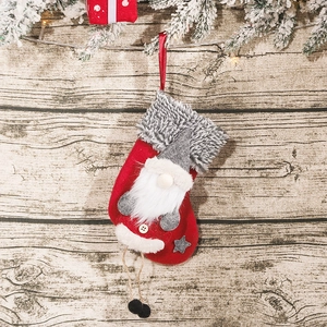 Chaussette de Noël rouge avec gnome et jambes suspendues sur fond de bois