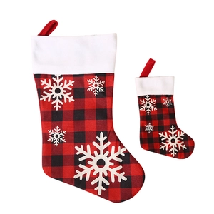 Set of two red and black buffalo plaid Christmas stockings with white snowflake appliques