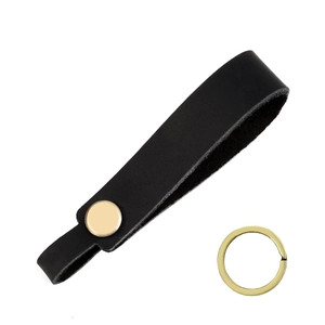 Detail of black crazy horse leather keychain with brass snap and ring on white background