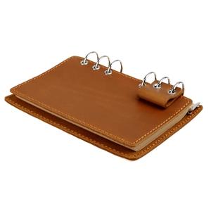 Détail macro du carnet en cuir marron avec classeur en métal à six trous et porte-stylo