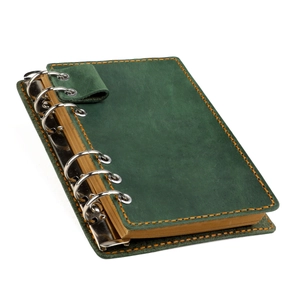 Détail d'un carnet en cuir vert foncé avec coutures oranges et anneaux de reliure argentés