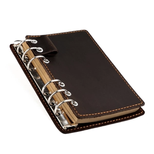 Détail d'un carnet de notes vintage en cuir marron avec coutures orange et anneaux argentés