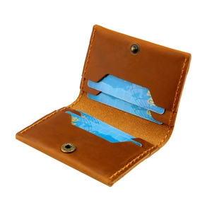 Detail of vintage crazy horse leather card holder with hand-stitched edges and brass snap