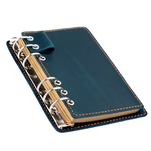 Détail du carnet en cuir vintage bleu avec surpiqûres oranges et anneaux en métal