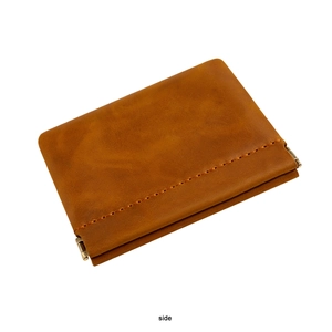 Macro side view of retro brown leather coin pouch with visible manual stitching