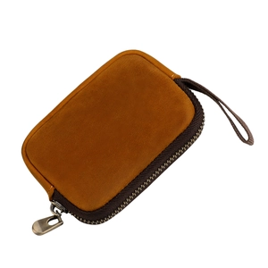 Close-up of a vintage ginger leather coin purse with bronze zipper and hand strap