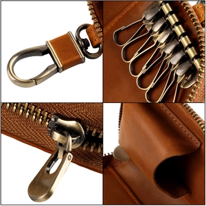 Close-up of vintage leather car key case with bronze hooks and smooth zipper detail