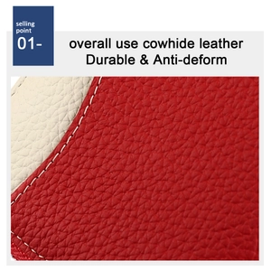 Close-up of red and beige cowhide leather with pebble texture and white stitching details