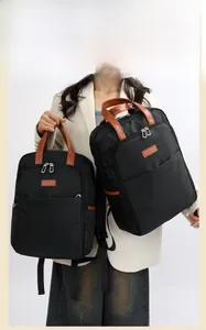 Detail of durable black nylon backpack featuring brown leather handle and silver metal zipper