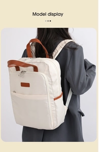 Detail of cream canvas backpack with brown leather handle and zip trim on model