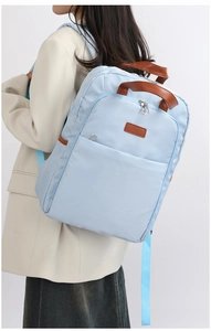 Light blue nylon backpack with leather handle shown on model in a professional studio