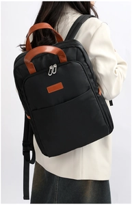 Detail of minimalist black laptop backpack with leather handle and large front zip pocket