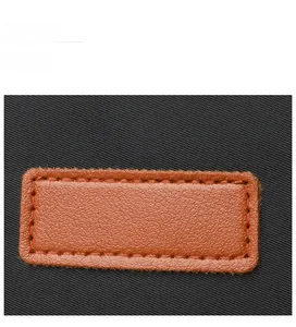Close-up of black woven fabric with a brown lychee pattern leather patch and stitching