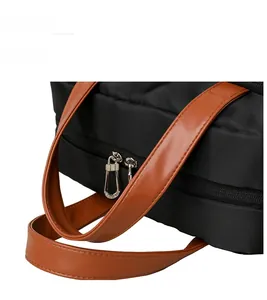 Detail of comfortable brown leather handles and dual silver zippers on black nylon backpack