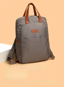 Detail of grey nylon backpack featuring brown leather handles and side bottle pocket