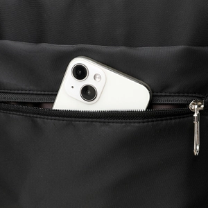 Close-up of hidden pocket on black nylon backpack showing storage for a smartphone