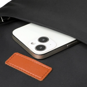 Detail of waterproof nylon laptop backpack with brown leather patch and phone pocket