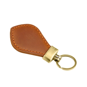 Detail of vintage caramel brown leather car keychain with brushed antique gold metal ring