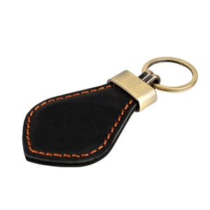 Close-up of black leather keychain with orange stitching and vintage bronze metal clip