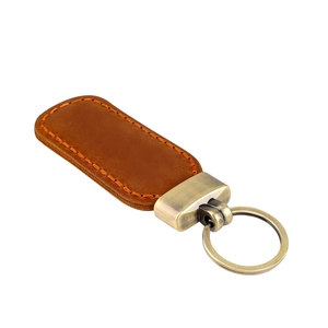 Detail of vintage brown crazy horse leather keychain with bronze metal ring and orange stitching